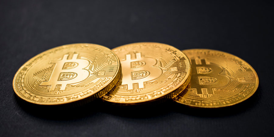 three pieces of gold bitcoins on top of a black surface